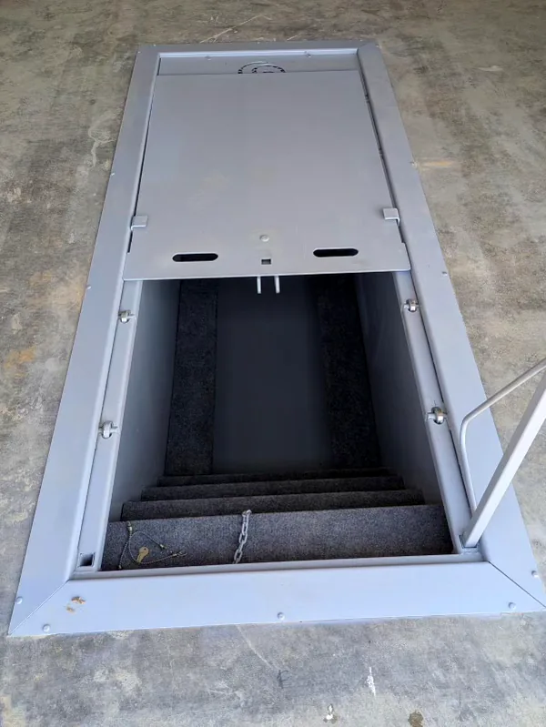 Garage storm shelter opened to show carpeted stairs and interior access
